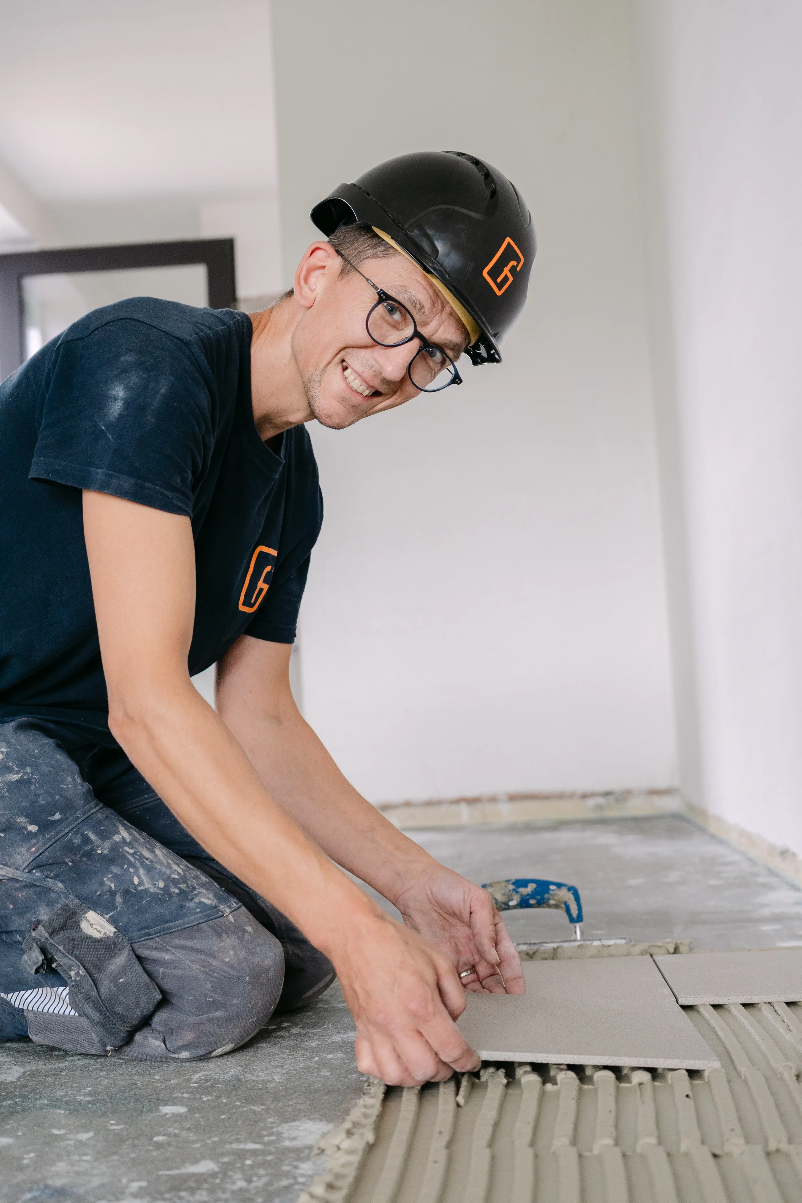 Monteur legt tegels op de vloer in een nieuwbouwwoning