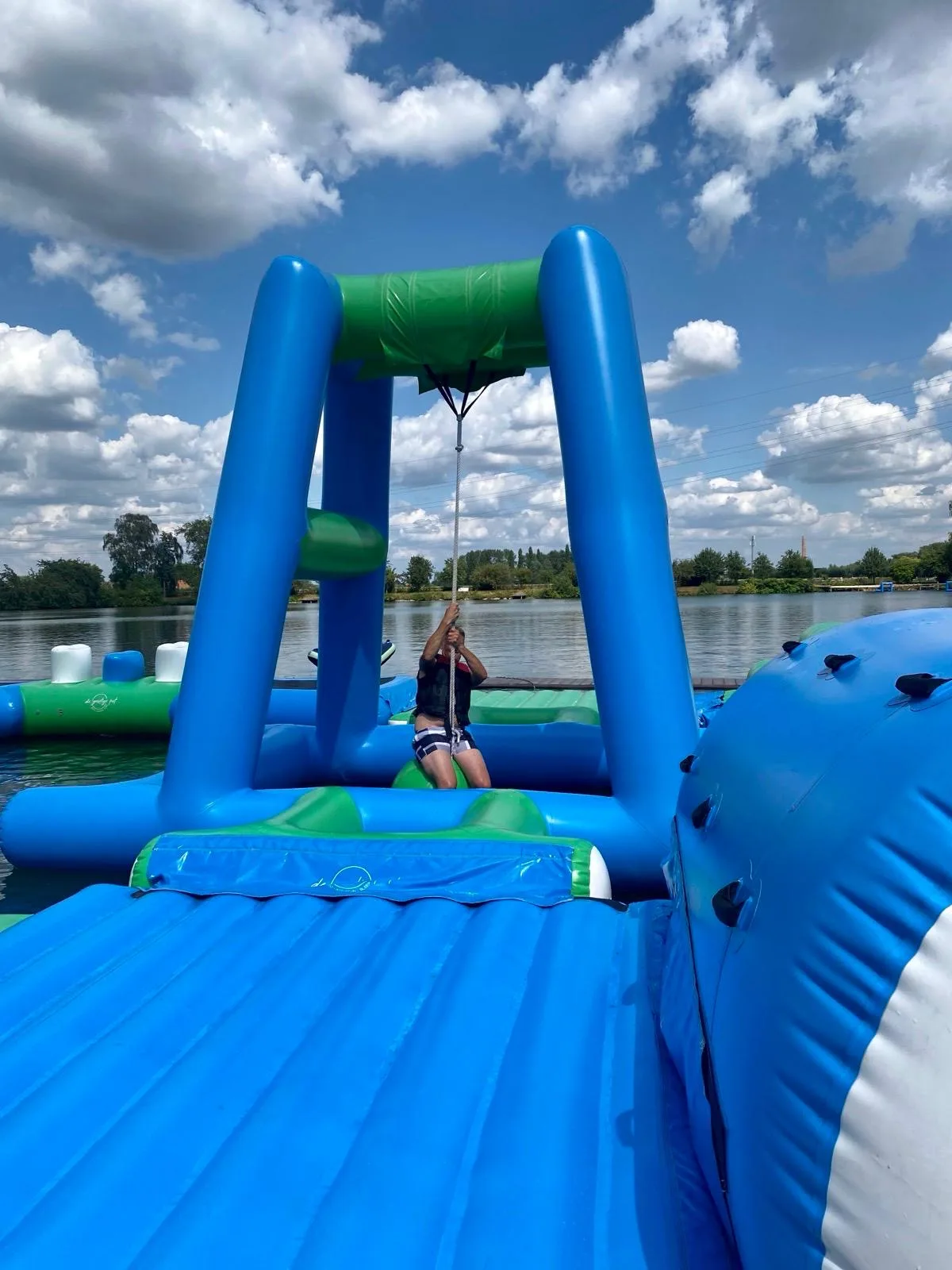 Een collega hangt aan het touw van het waterparcours tijdens de teambuilding