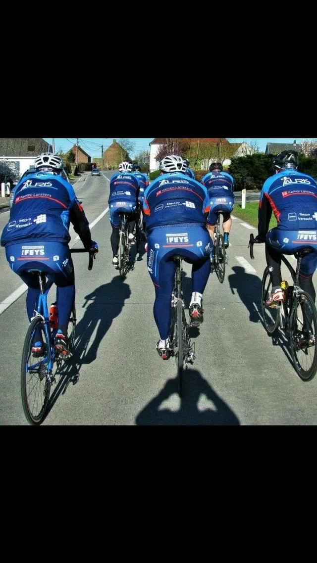 Groep wielrenners in blauwe teampakken rijdt op een landelijke weg