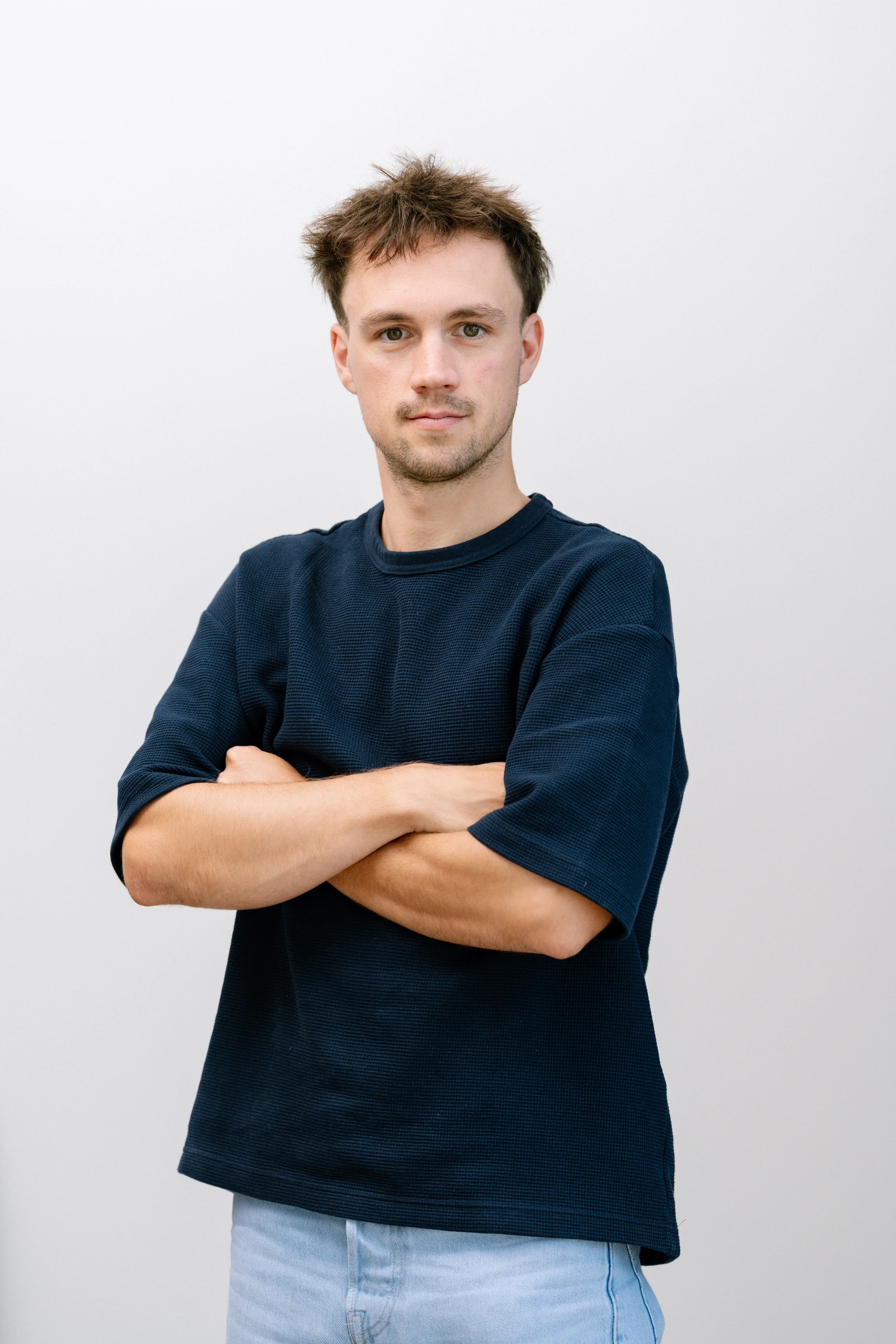 Portretfoto van een man met donker haar in donkerblauw shirt met gekruiste armen