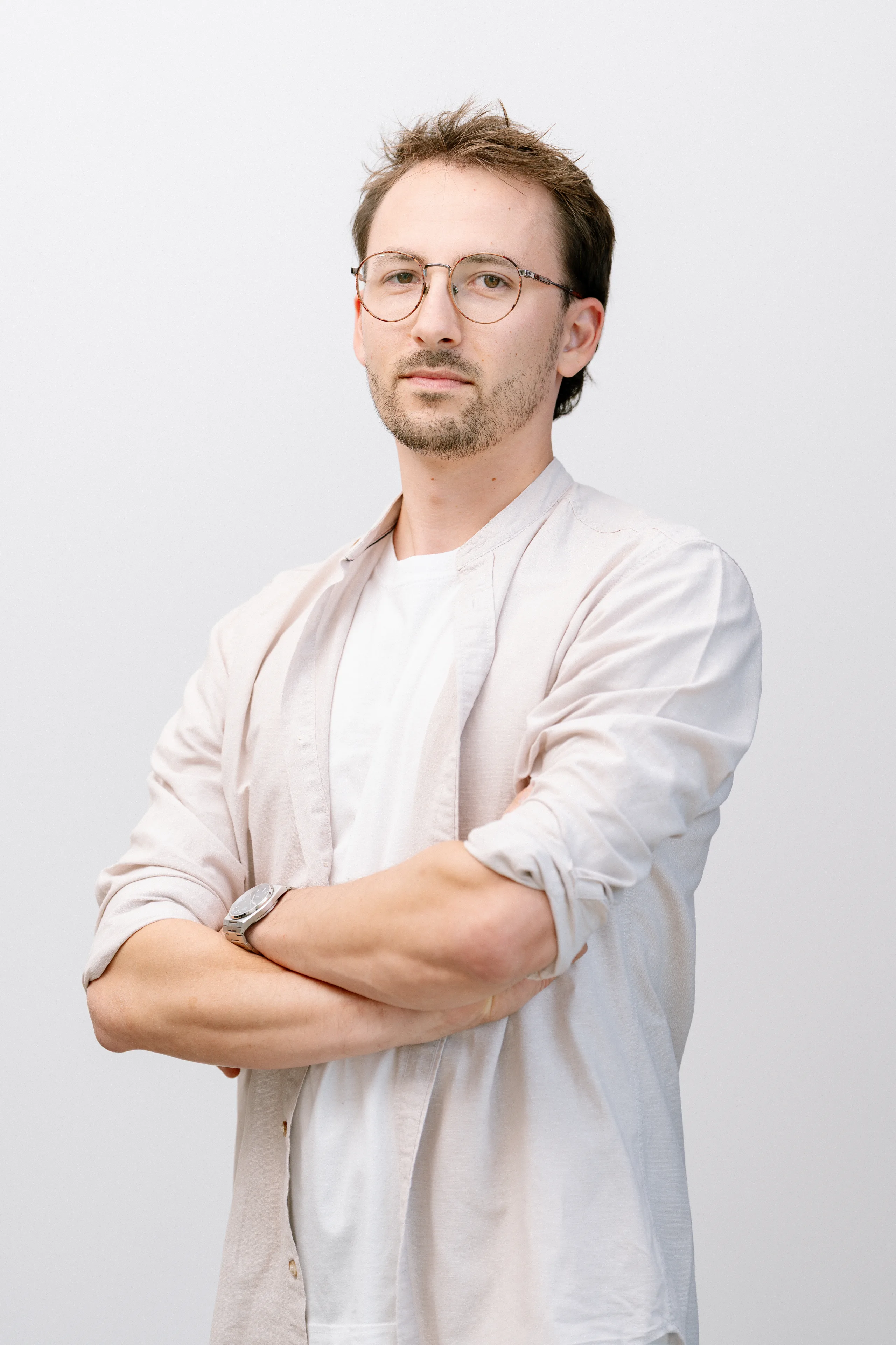 Portret van een man met bril en lichte kleding tegen een witte achtergrond