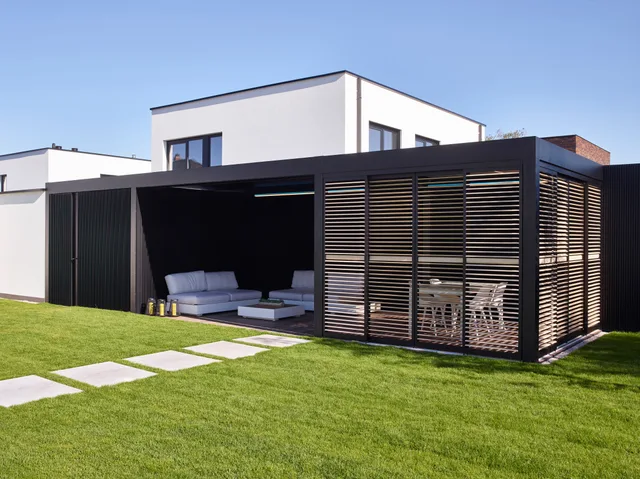 Moderne woning met zwarte stalen terrasoverkapping en lamellenscherming aan de tuinzijde