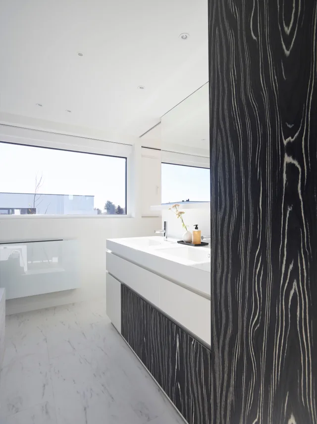 Moderne badkamer met wit wastafelmeubel, marmerenvloer en donker houten accent naast groot raam met uitzicht