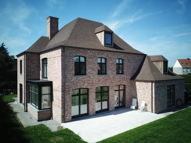 Nieuwbouwwoning in baksteen met mansardedak, dakkapel en grote raampartijen aan de tuinzijde